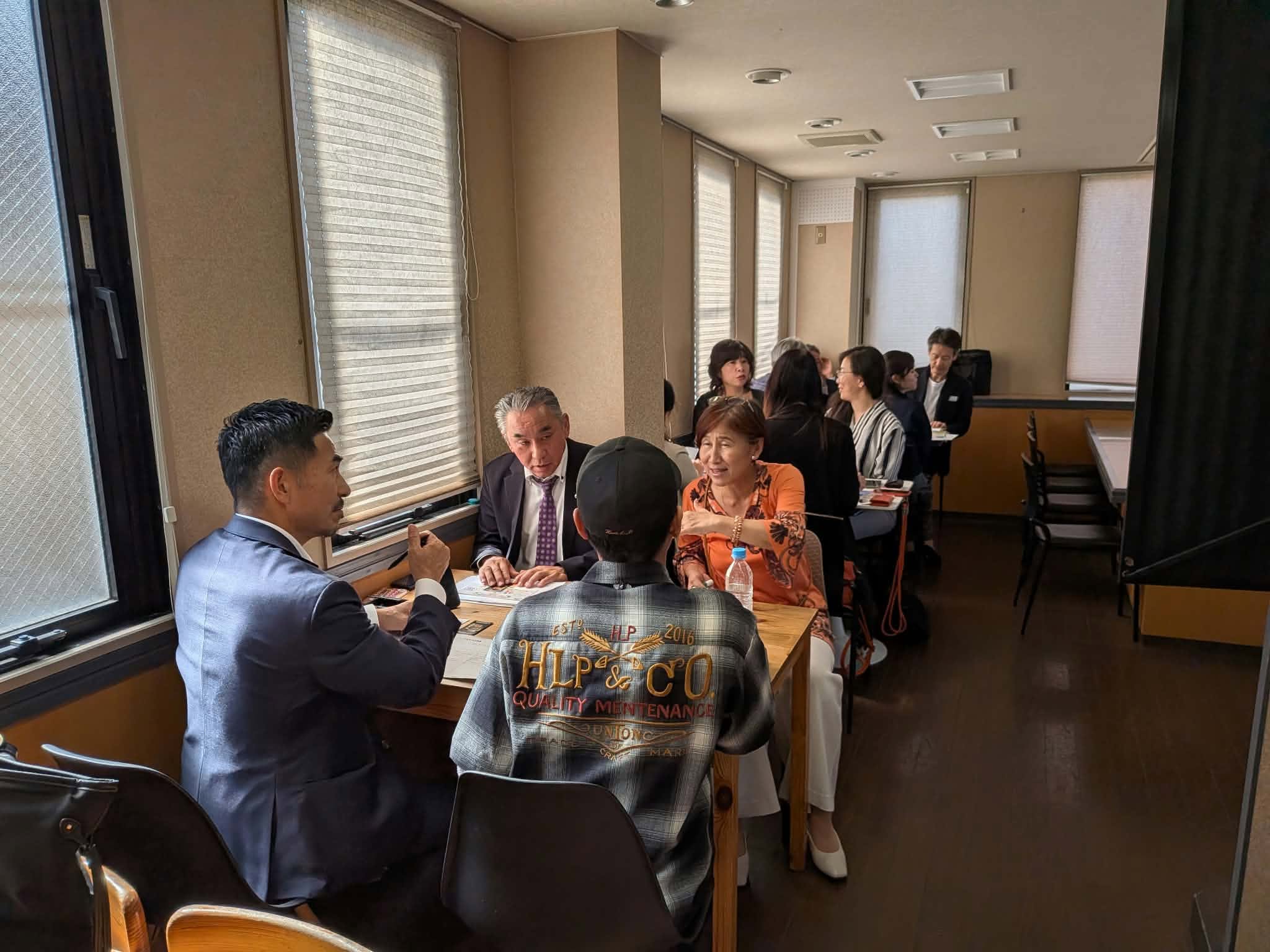 資料を広げたテーブルを囲み、仕事について話し合う例会参加者