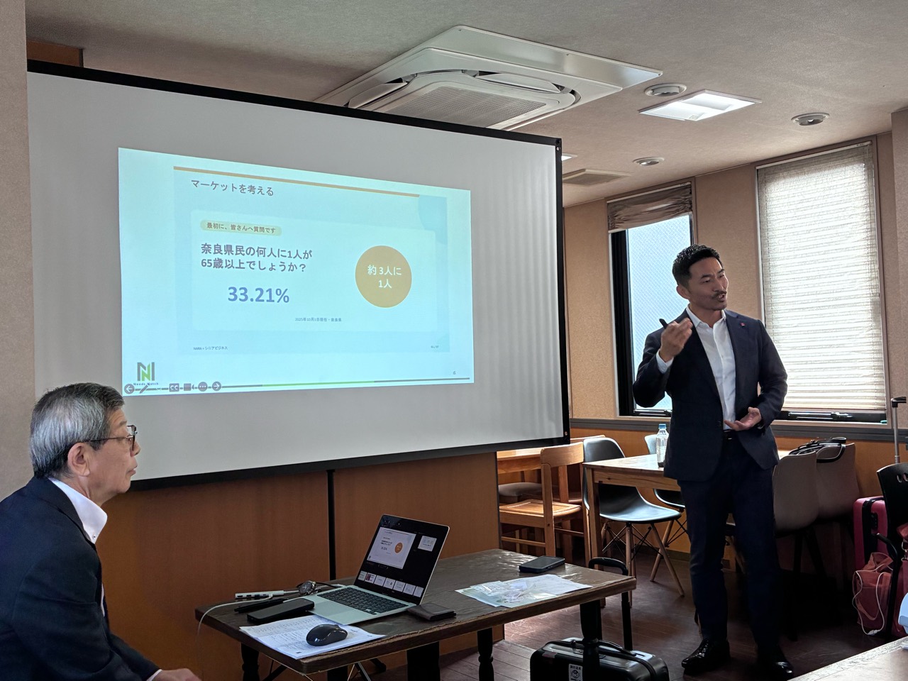 奈良のシニア支援をテーマに、スクリーンの前でミニセミナーを行う丹羽篤蔵さん